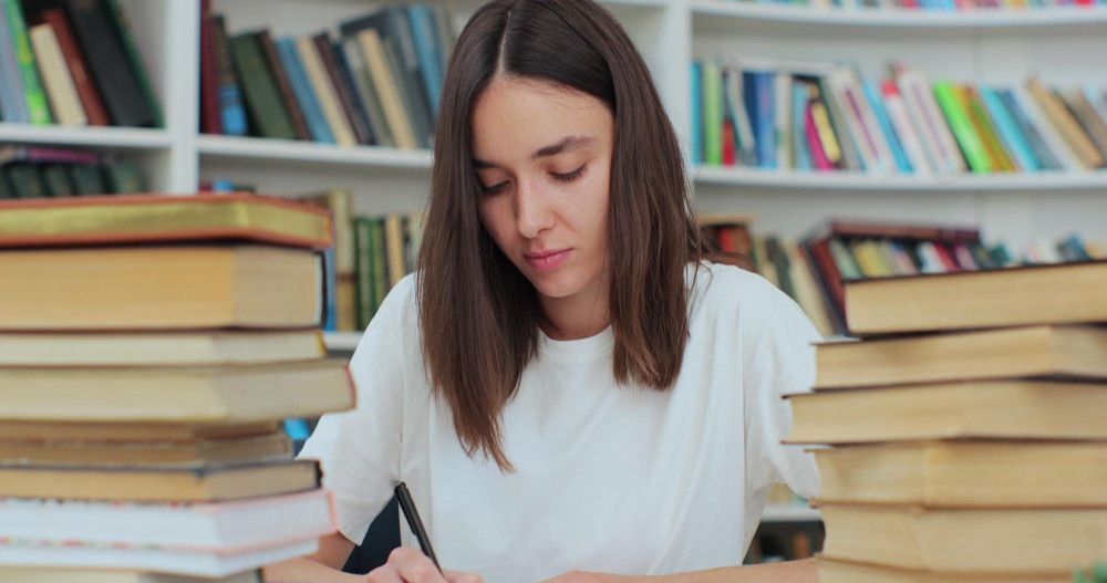 Student collecting information from different books caucasian girl in white tshirt gathering data for the paper self education concept